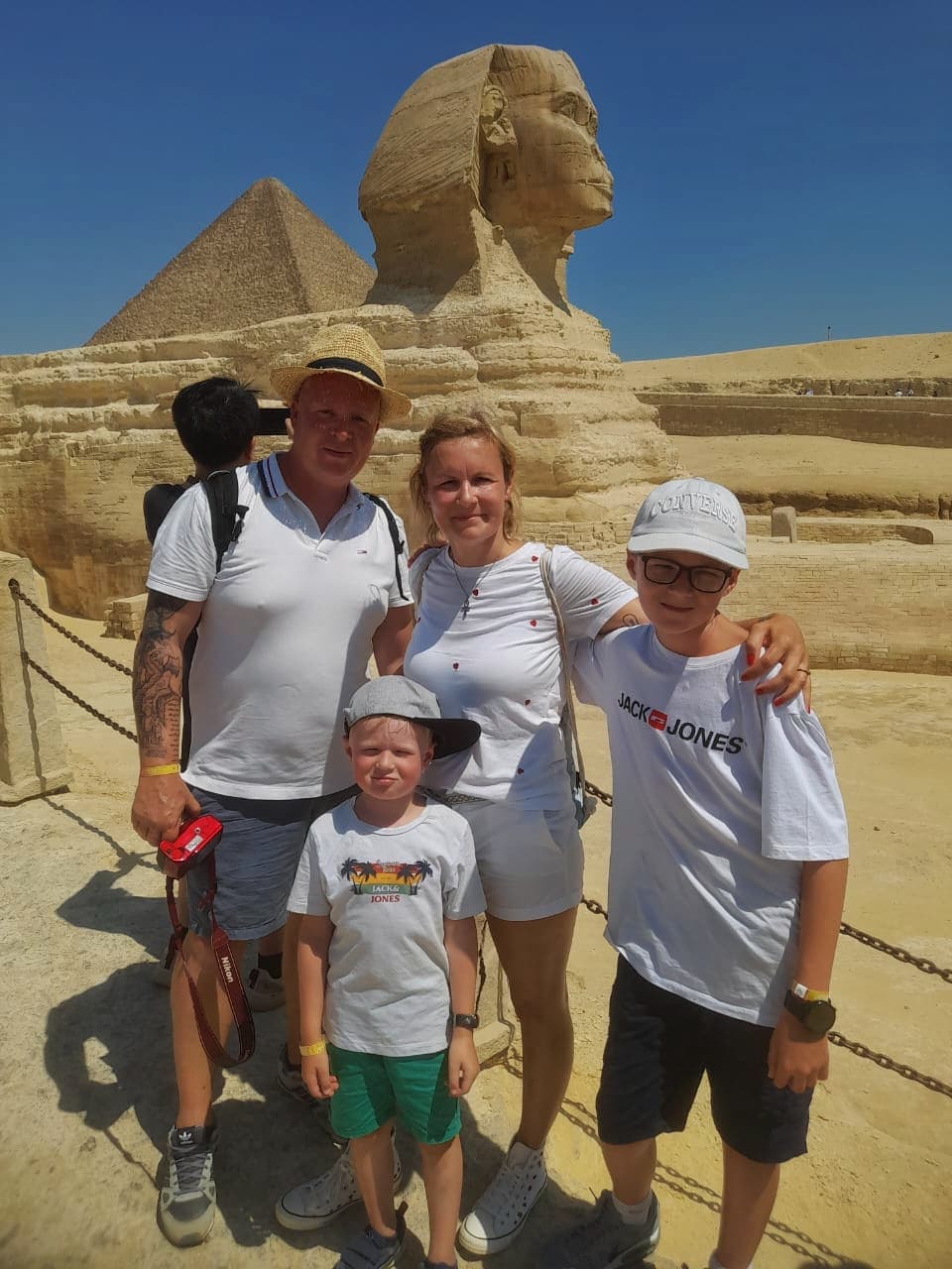 Family of four posing in front of the Great Sphinx and a pyramid in Giza.