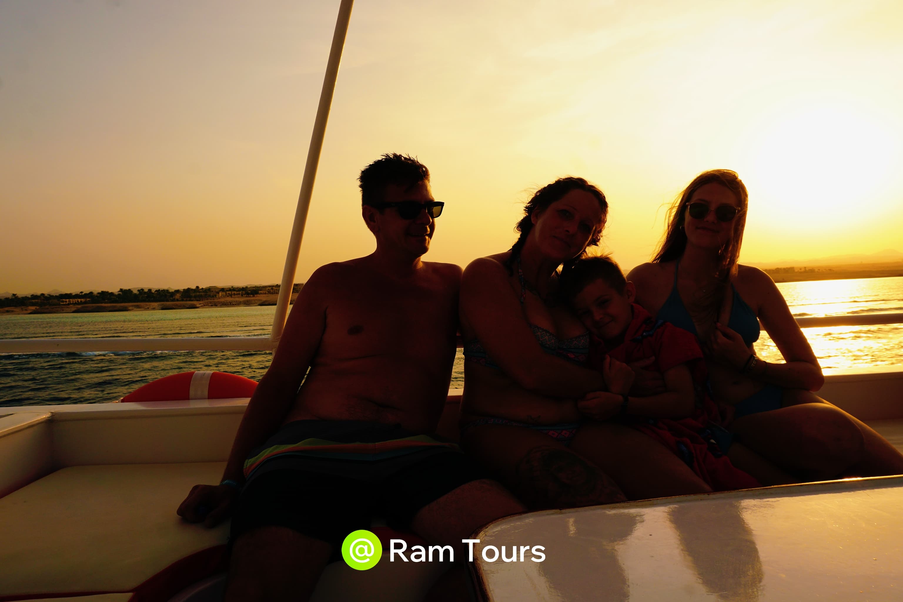 Silhouetted family of four on a boat during a golden sunset over the water.